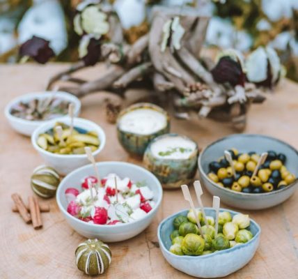 A rustic winter spread of appetizers on a wooden surface, featuring vegetables and dips.