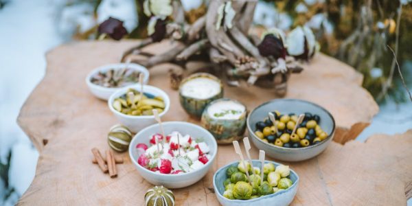 A rustic winter spread of appetizers on a wooden surface, featuring vegetables and dips.