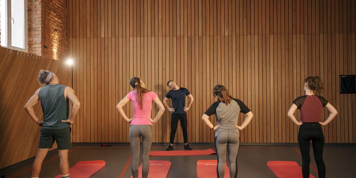 Men and women performing stretching exercises on mats in a fitness class